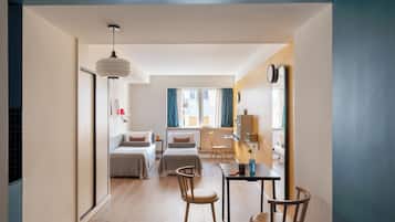 A modern hotel room with a bed, two chairs, a desk, and a large mirror.