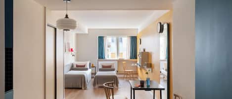 Een moderne hotelkamer met een bed, twee stoelen, een bureau en een grote spiegel.