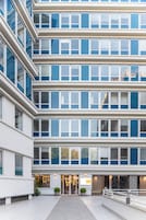 Un hotel a più piani con una facciata moderna, ampie finestre e un ingresso centrale con un cartello.