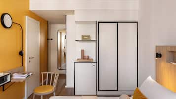 Un dormitorio moderno con cama, escritorio, silla, armario y mesita de noche.