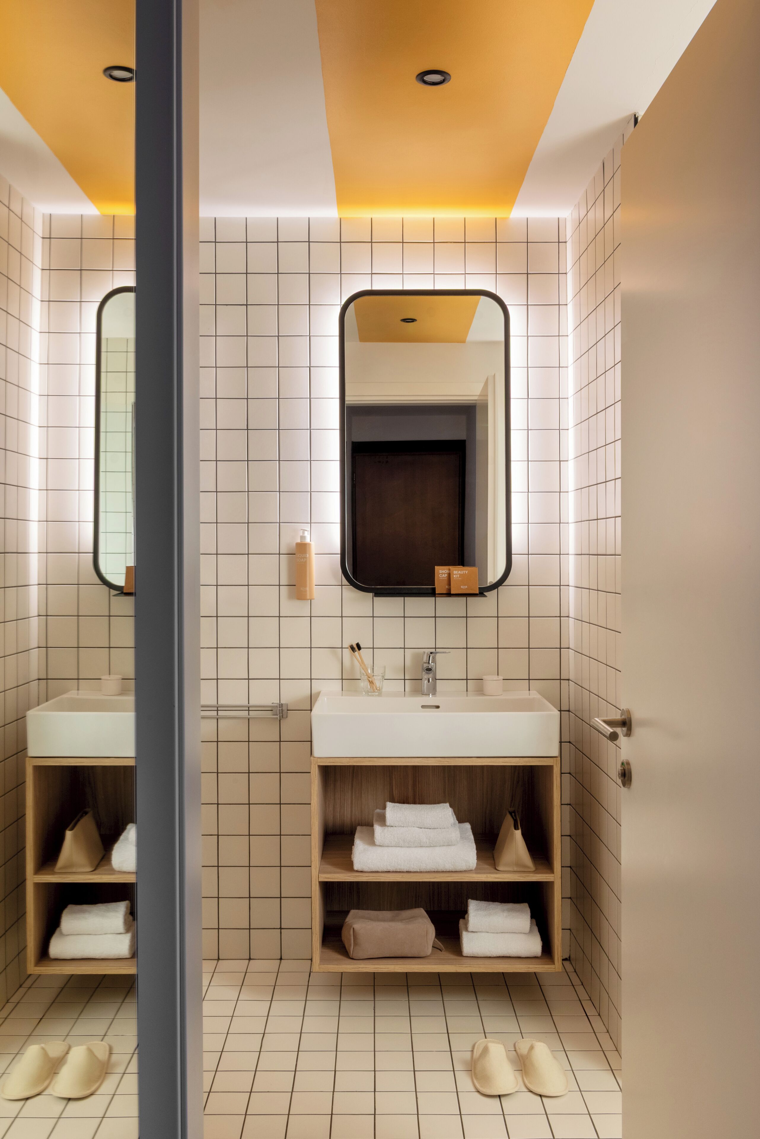 Un baño moderno con dos lavamanos, un espejo y una zona de ducha.