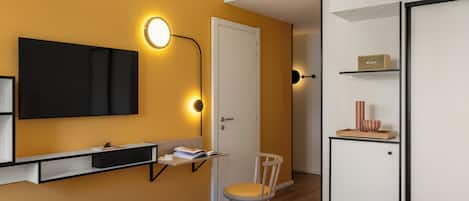 A modern bedroom with a bed, bedside table, lamp, wardrobe, and a desk with a chair.