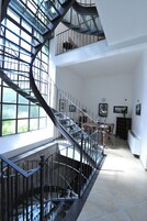 Un interior espacioso con una llamativa escalera de caracol, ventanas amplias y un comedor.