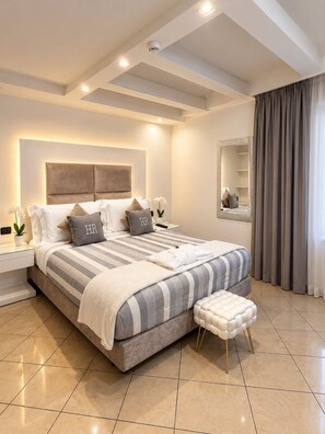 Un dormitorio moderno con una cama grande, mesitas de noche, un tocador, un espejo y una ventana con cortinas.