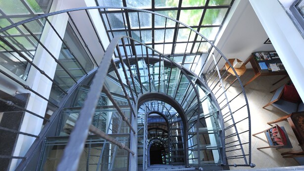 A spiral staircase with metal railings and glass panels, leading to an upper floor. - Hotel Rivoli (Sorrento)