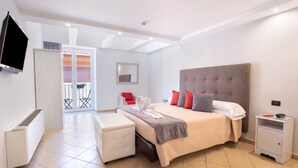 A modern hotel room with a large bed, a TV, a small table, and a chair. - Hotel Rivoli (Sorrento)