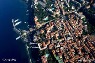 Vista aérea de un pueblo costero con un puerto deportivo, edificios históricos y cielo despejado.