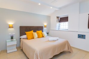 Ein ordentlich eingerichtetes Schlafzimmer mit einem Bett, Nachttischlampen und einem Fenster mit Vorhängen.