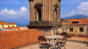 A rooftop terrace with a hot tub, two chairs, and a table. - Hotel Rivoli (Sorrento)