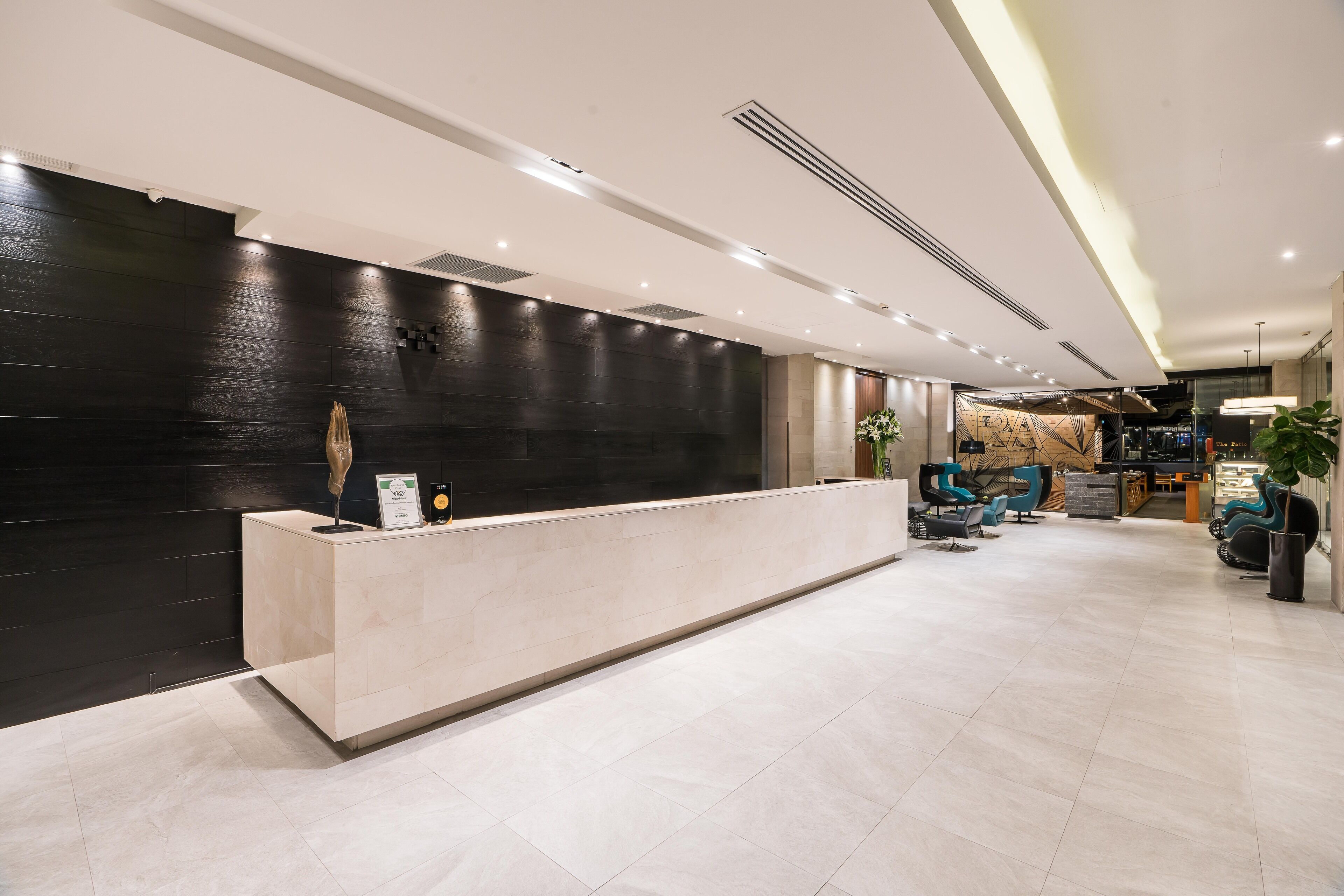 A modern reception area with a dark wall, a light-colored reception desk, and a seating area with blue chairs.