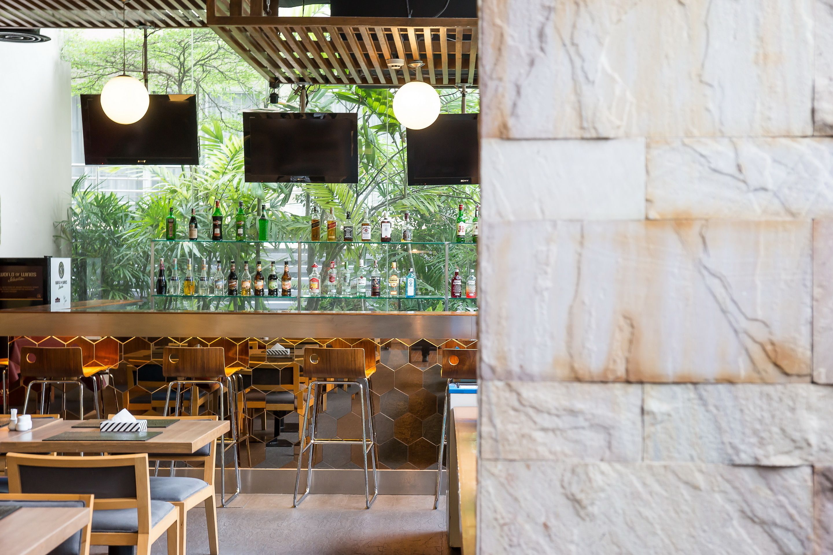 Un espace bar doté d’un comptoir en verre, de plusieurs tabourets et offrant une vue sur la verdure environnante.