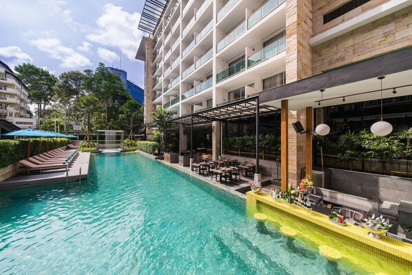A hotel with a swimming pool, outdoor seating, and a view of a mountain.
