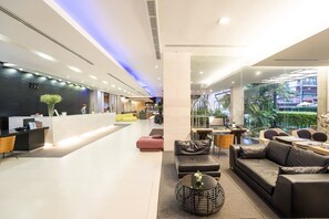 En moderne lobby med reception, siddeområder og store vinduer med udsigt til det fri.