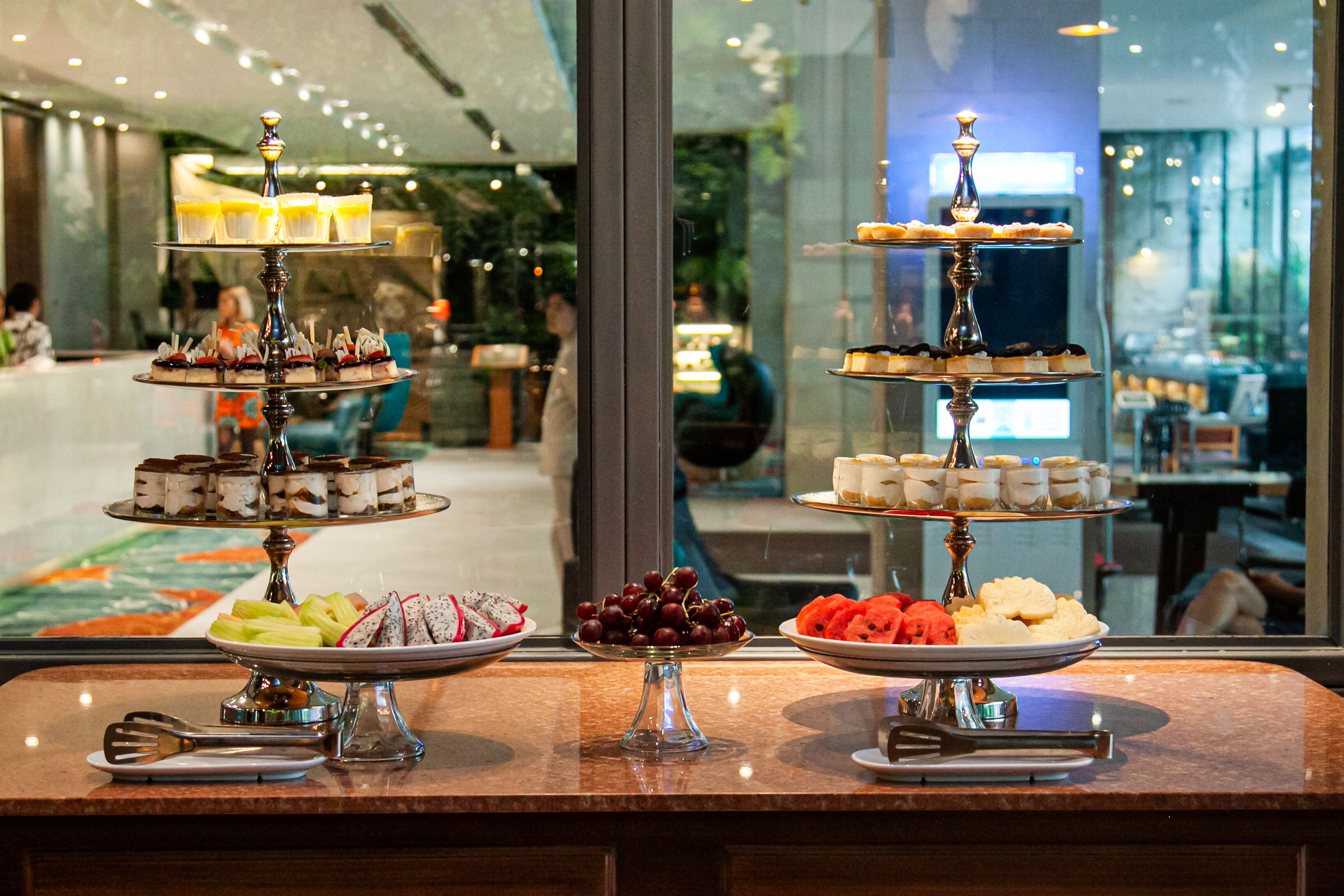 Een buffettafel met meerdere lagen desserts en fruit.
