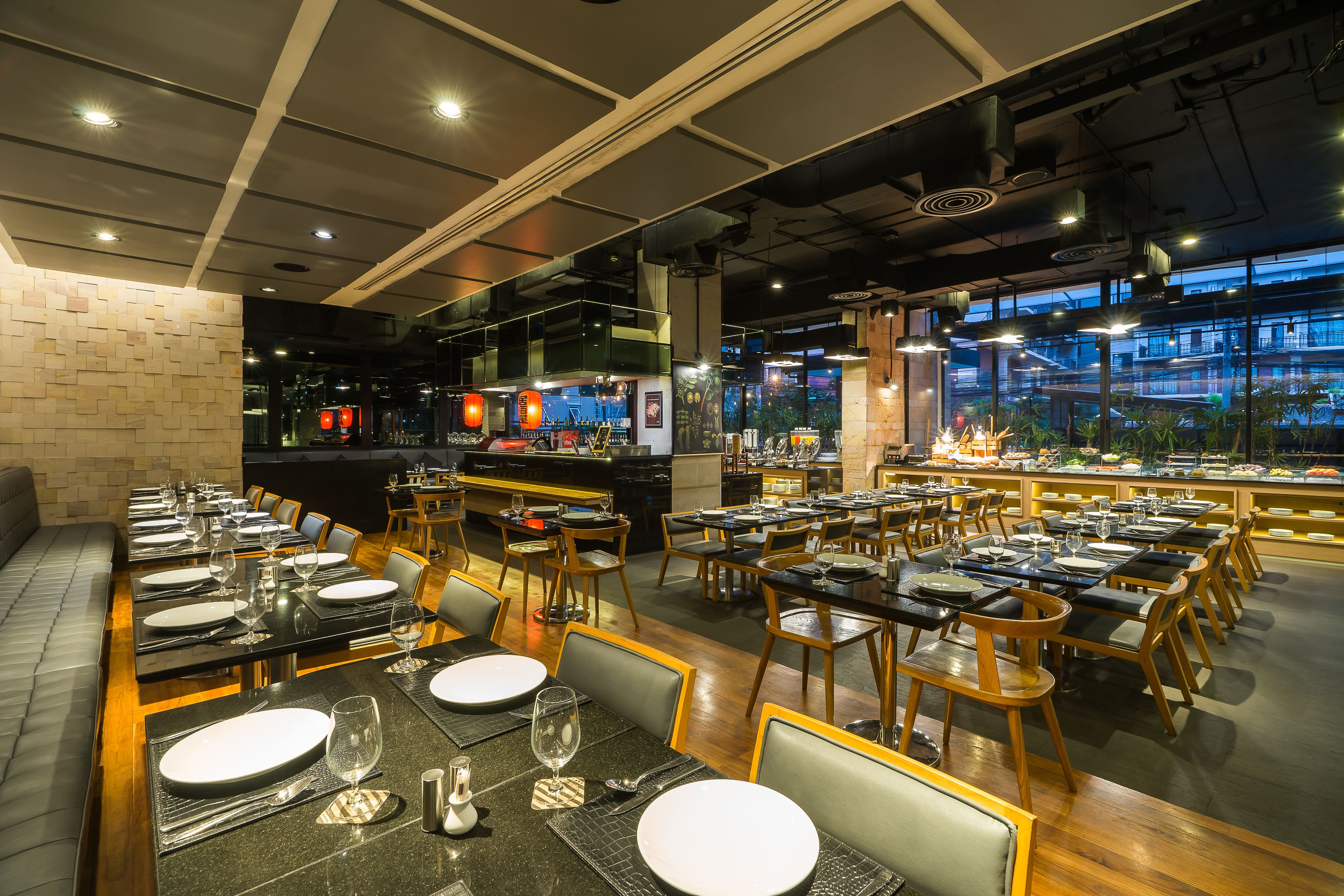 A restaurant with multiple dining tables and chairs, a bar area, and a view of the cityscape through large windows.