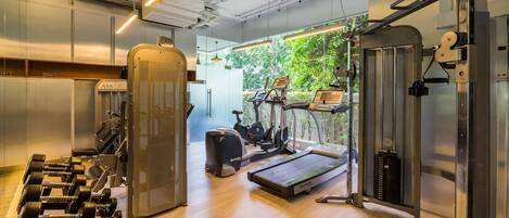 Un gimnasio con equipo de ejercicio, una cinta de correr y un espejo grande.