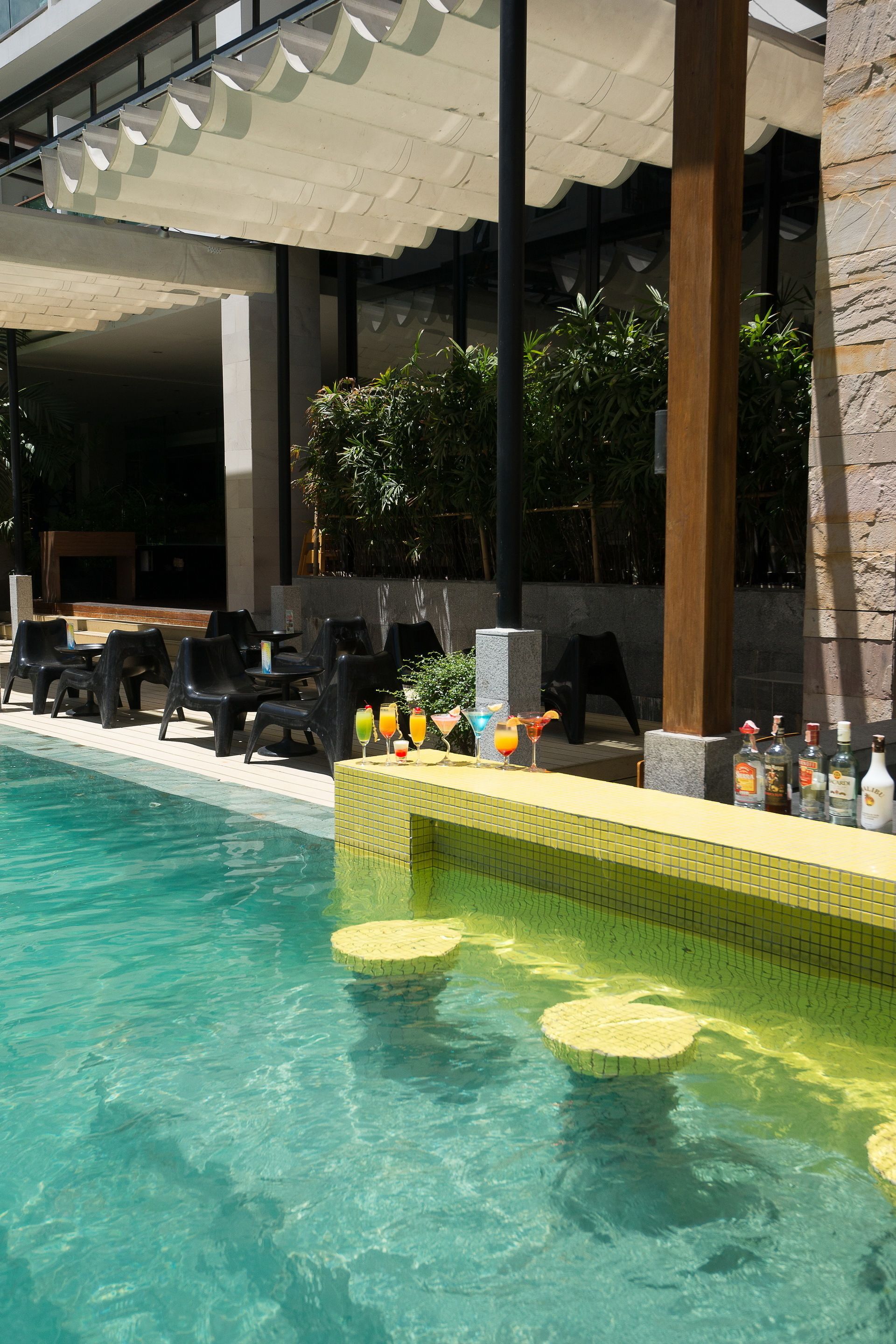 A poolside area with a bar, lounge chairs, and a tiled deck.