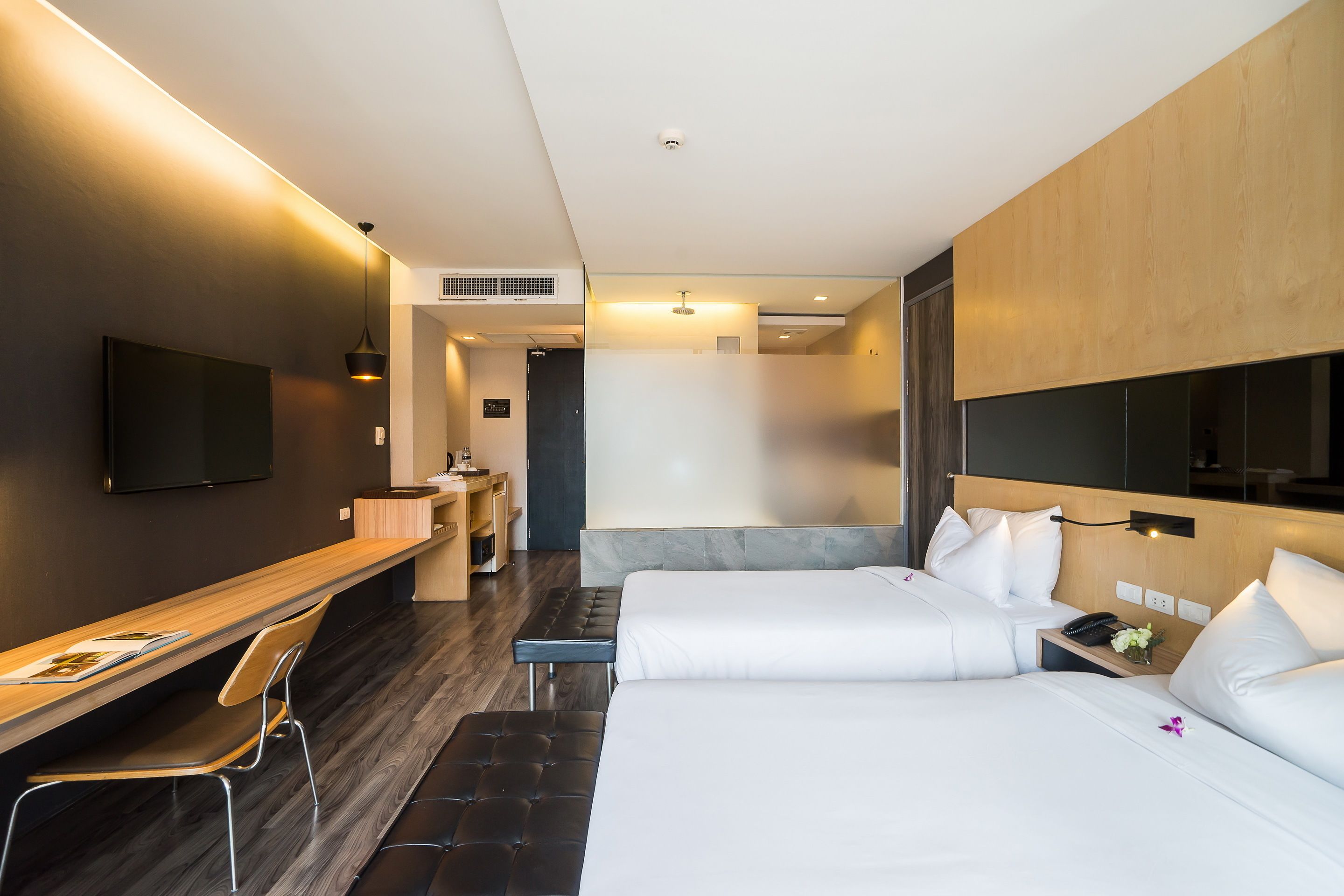 A modern hotel room with a large bed, a desk, and a TV.