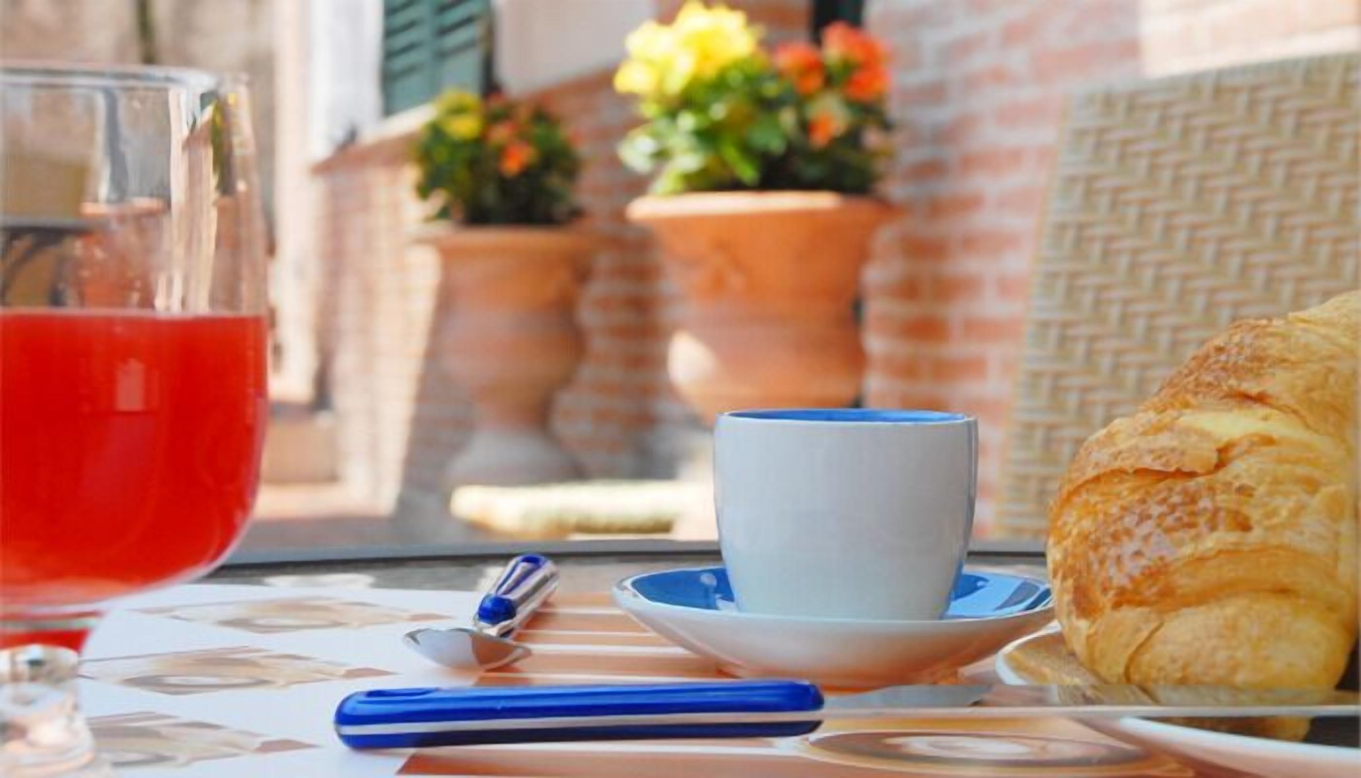 Una mesa con un vaso de bebida roja, una taza, un bolígrafo y un pastel.