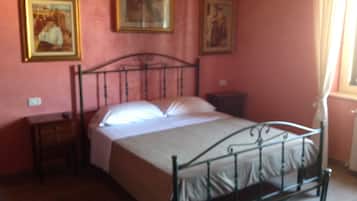 A bedroom with a metal bed frame, a bedside table, and a nightstand. There are three framed pictures on the wall.