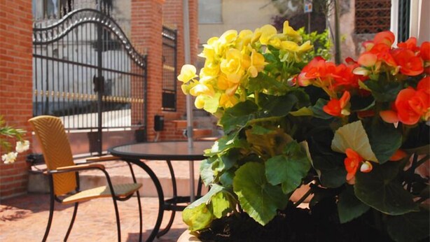 A patio with a brick wall, a metal gate, and a round table with chairs. - Villa Scotillo 1950 (Agropoli)