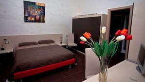 A bedroom with a bed, a desk, a chair, a vase with flowers, and a painting on the wall. - Villa Scotillo 1950 (Agropoli)