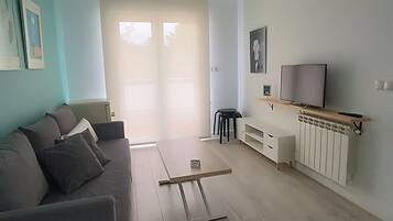 Un soggiorno con un divano, una TV su una mensola di legno e una ventola a soffitto.