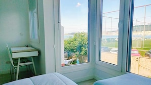 A room with a bed, a desk, and a window with a view of a parking lot and greenery. - Hotel Rodeiramar (Cangas)