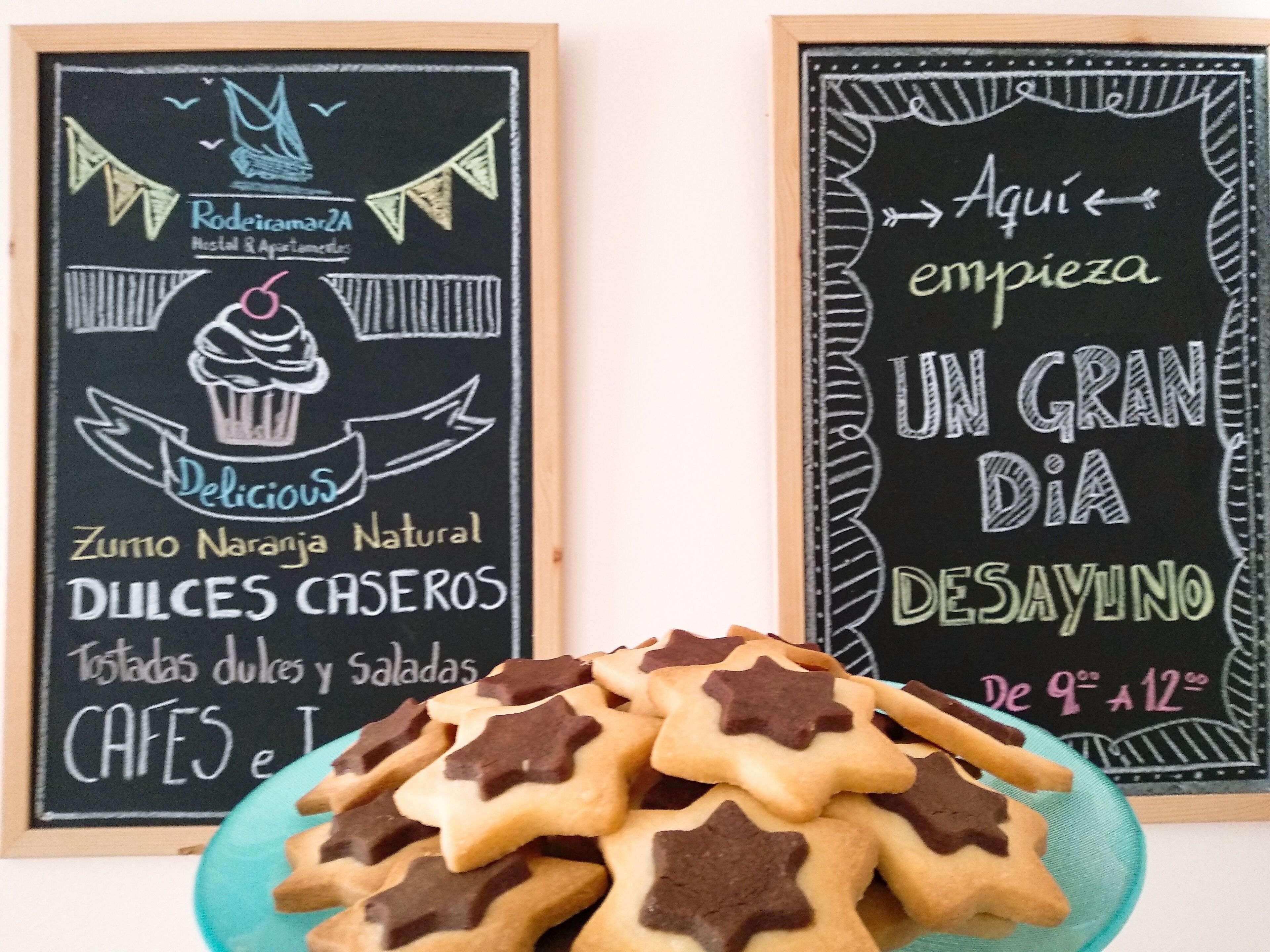 Dos pizarras publicitarias de una panadería y un café, con galletas con forma de estrella en primer plano.
