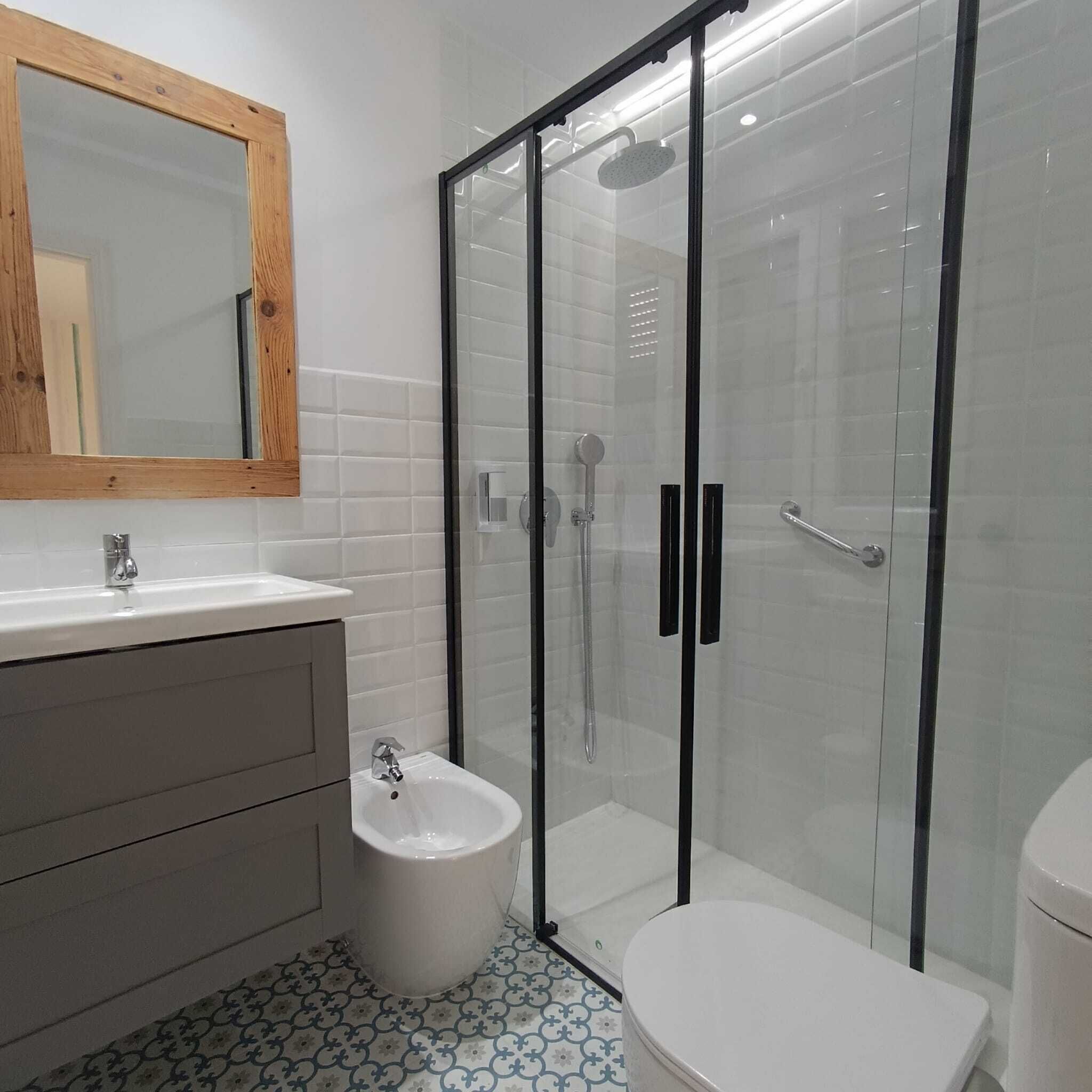 A modern bathroom with a glass-enclosed shower, a white sink, and a bidet.