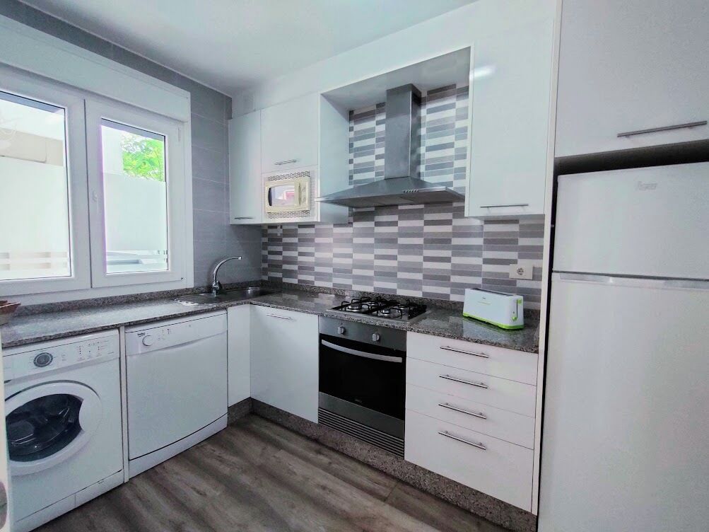 A modern kitchen with white cabinets, a gas stove, a microwave, and a built-in oven.