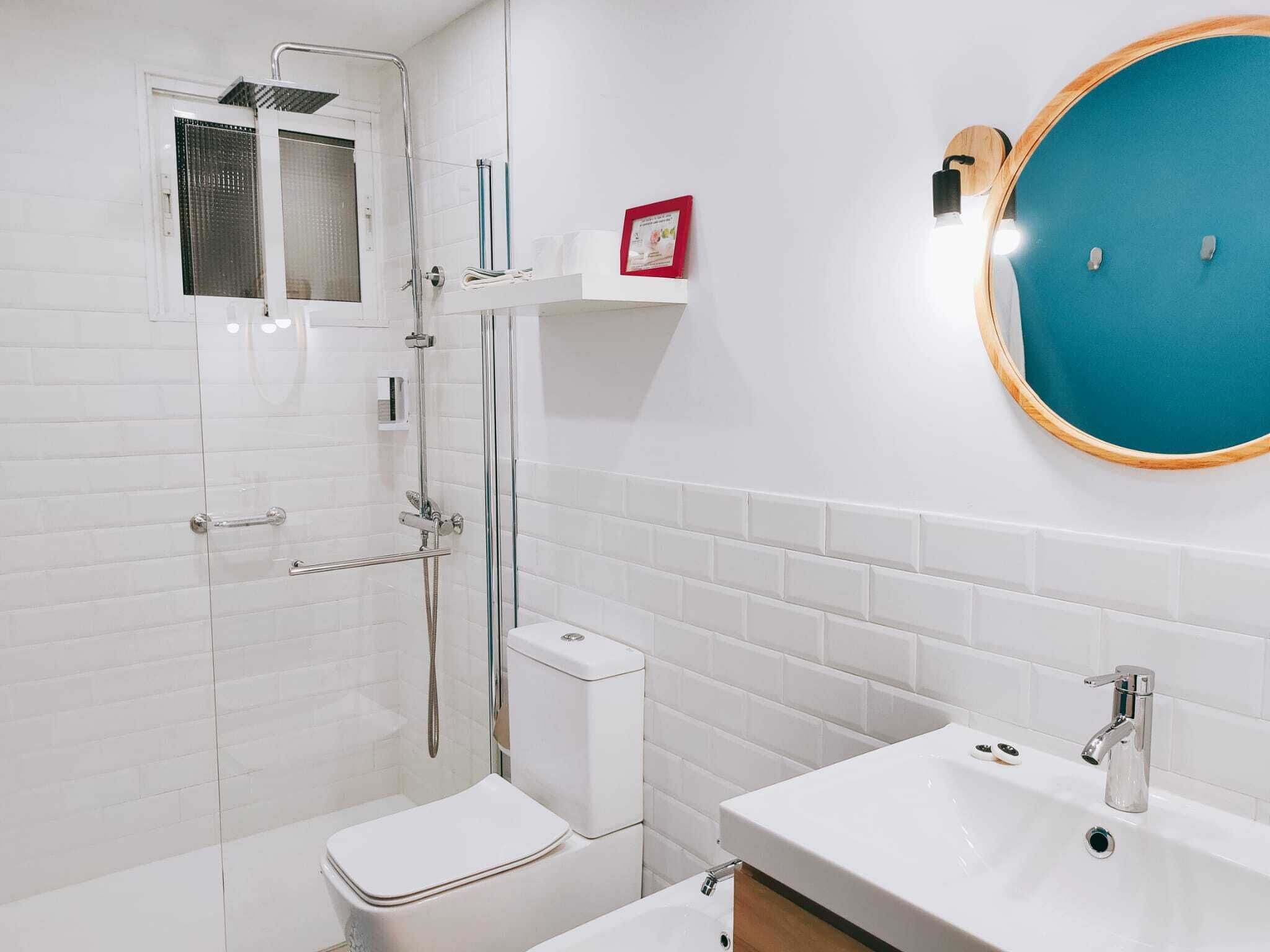 Ein modernes Badezimmer mit einer Duschkabine, einer weißen Toilette, einem Waschbecken mit Spiegel und einem spiegelbildenden blauen Rahmen.