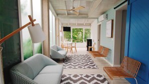 A spacious room with a ceiling fan, a painting on the wall, and a view of the outdoors through large windows. - Hotel Rodeiramar (Cangas)
