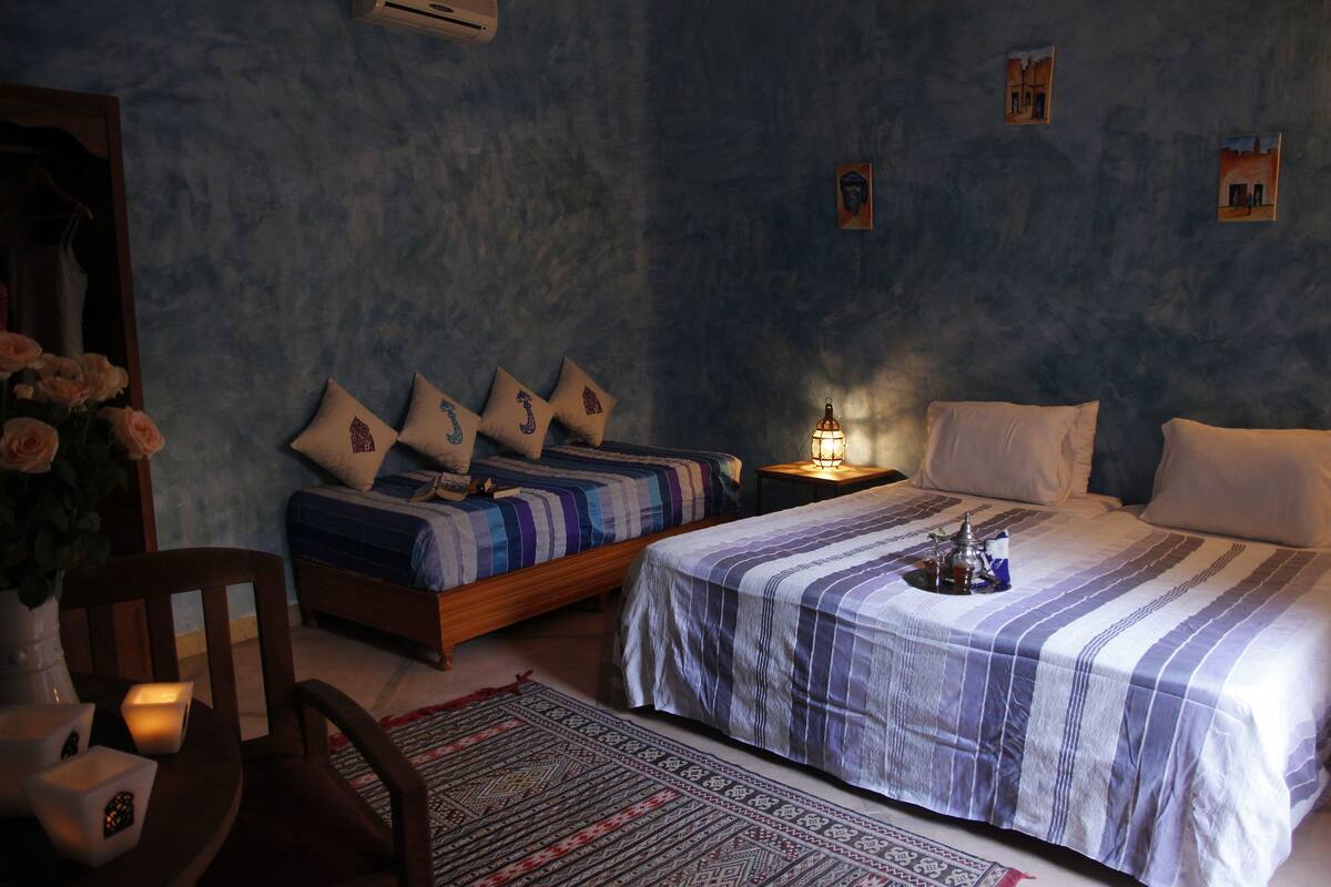 A bedroom with two beds, a nightstand, a chair, and a decorative rug.