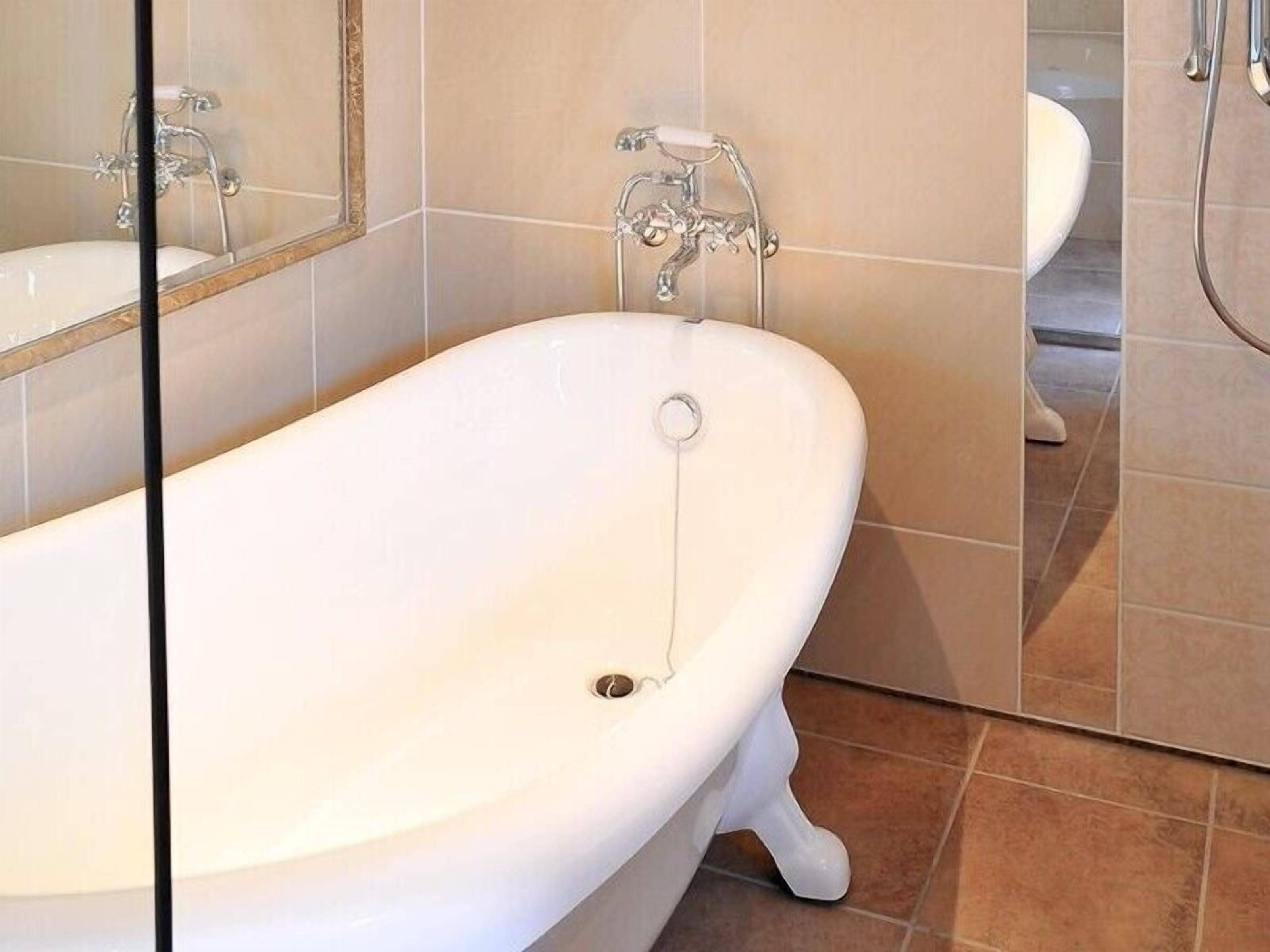 Ein Badezimmer mit einer weißen freistehenden Badewanne, einem weißen Waschbecken und einem Spiegel darüber.