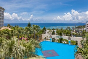 Un hôtel doté d’une piscine, de palmiers et offrant une vue sur l’océan.