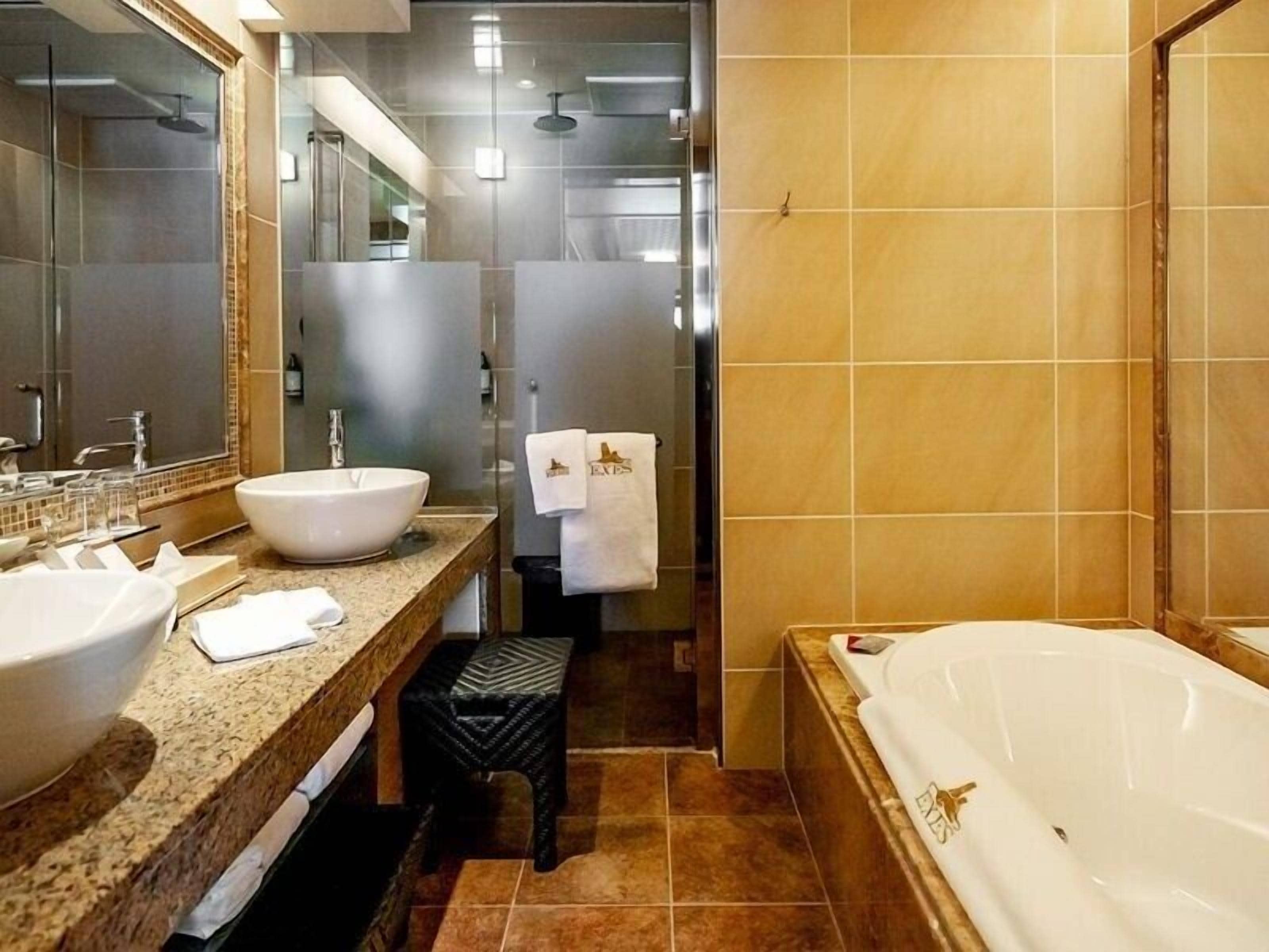 Une salle de bain moderne dotée d’une grande baignoire, de deux lavabos, d’un meuble-lavabo et d’un espace douche.