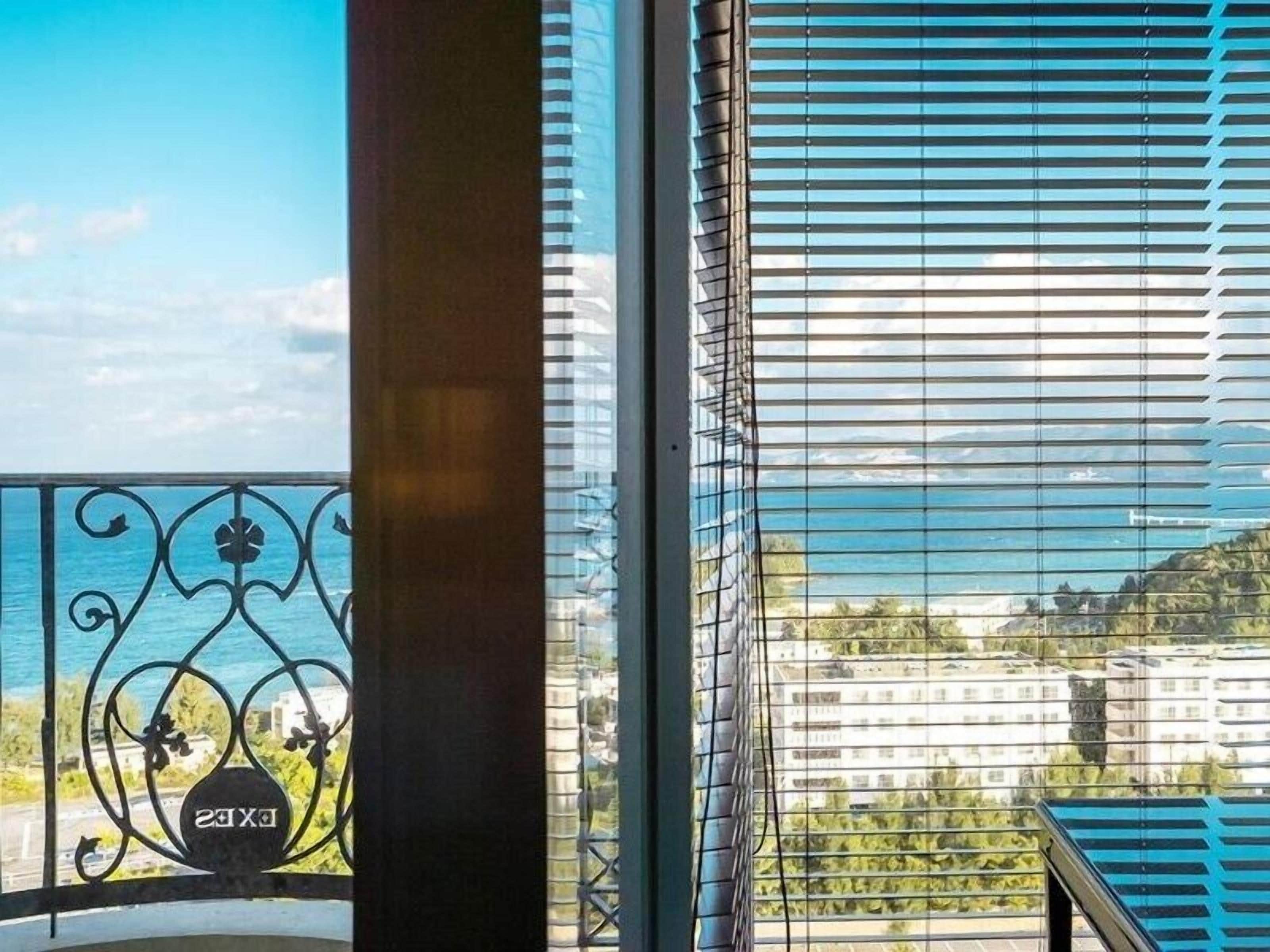 A balcony with a metal railing and a view of the sea and buildings.