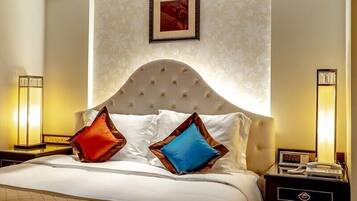 A hotel room with a large bed, two bedside lamps, a clock, and a framed picture on the wall.