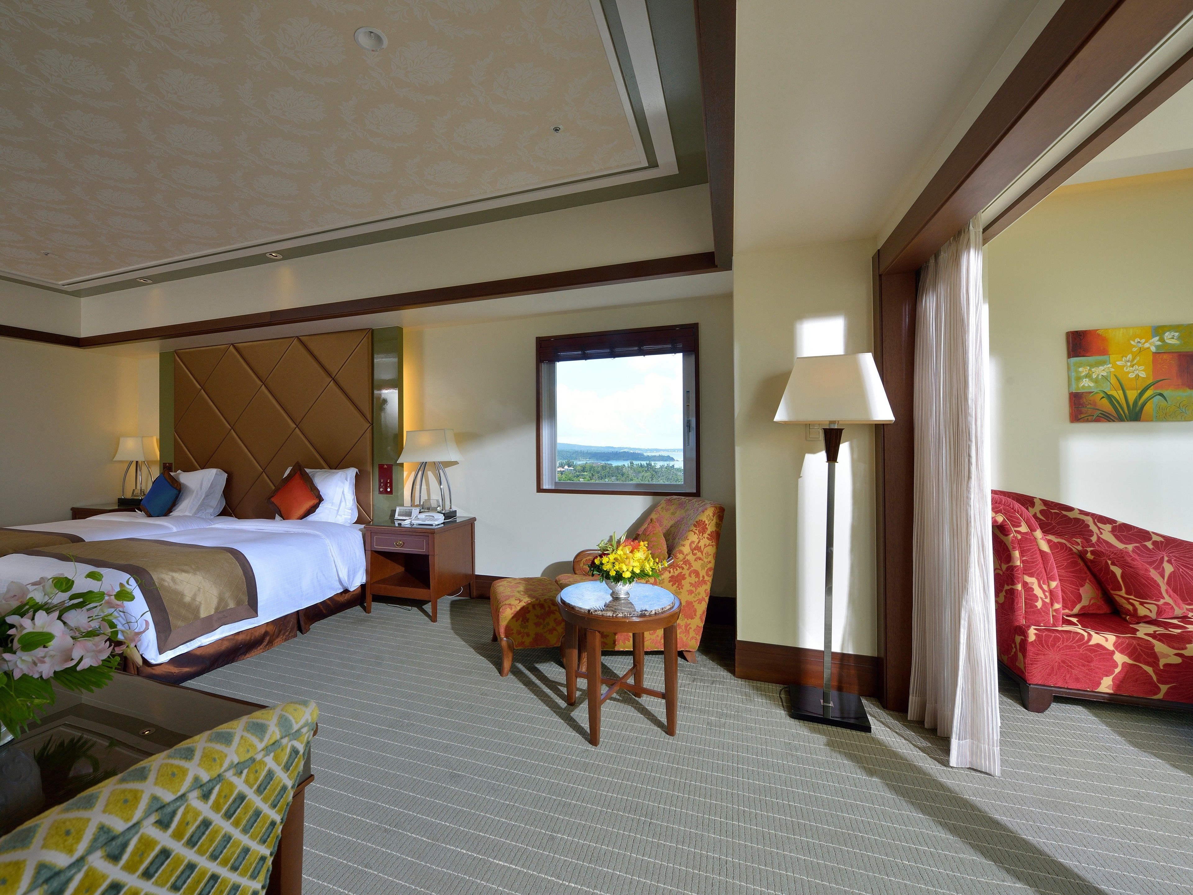 A hotel room with a bed, a desk, a chair, a sofa, and a window with a view.