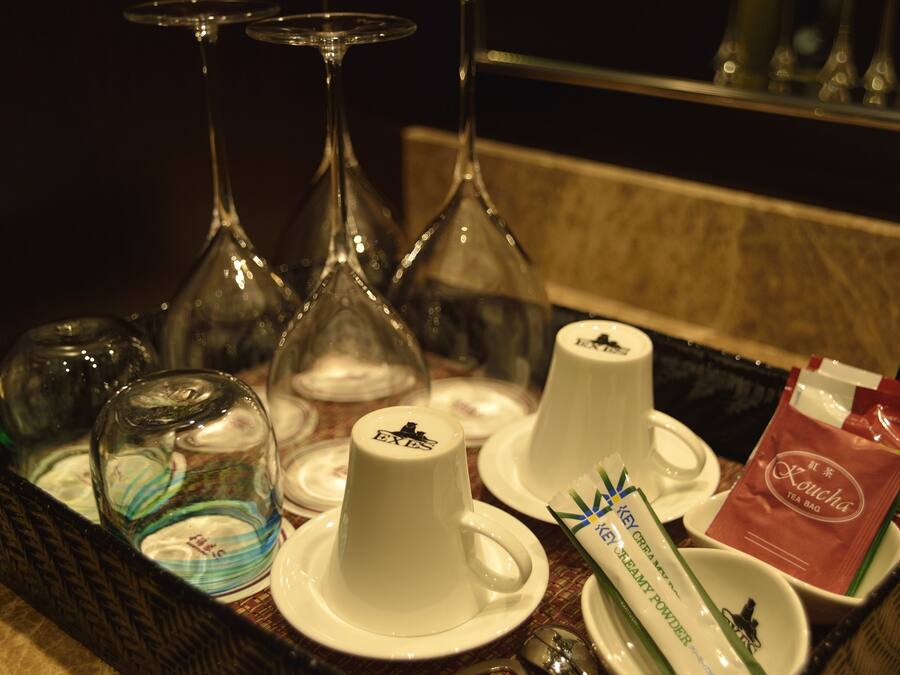 A tray with tea bags, a creamer, and glasses on a table.