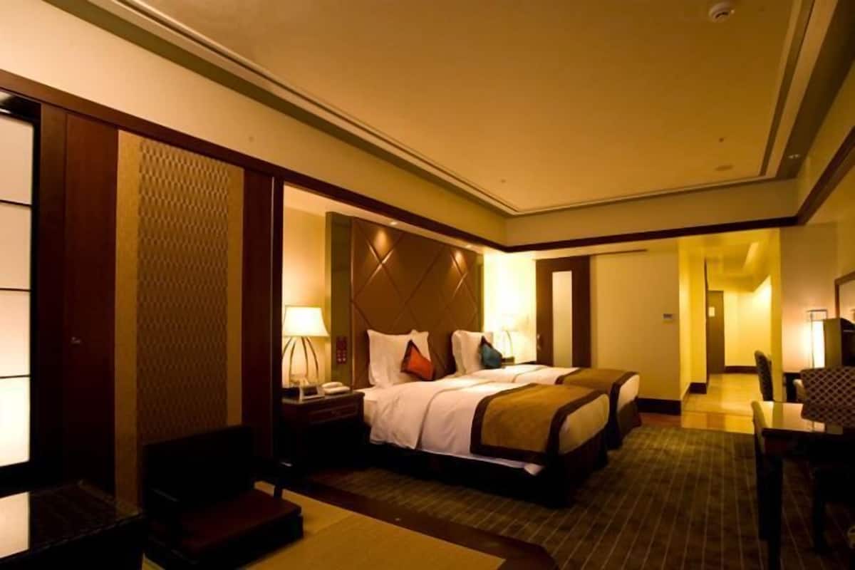 Ein Hotelzimmer mit zwei Betten, einem Schreibtisch und einem Stuhl.