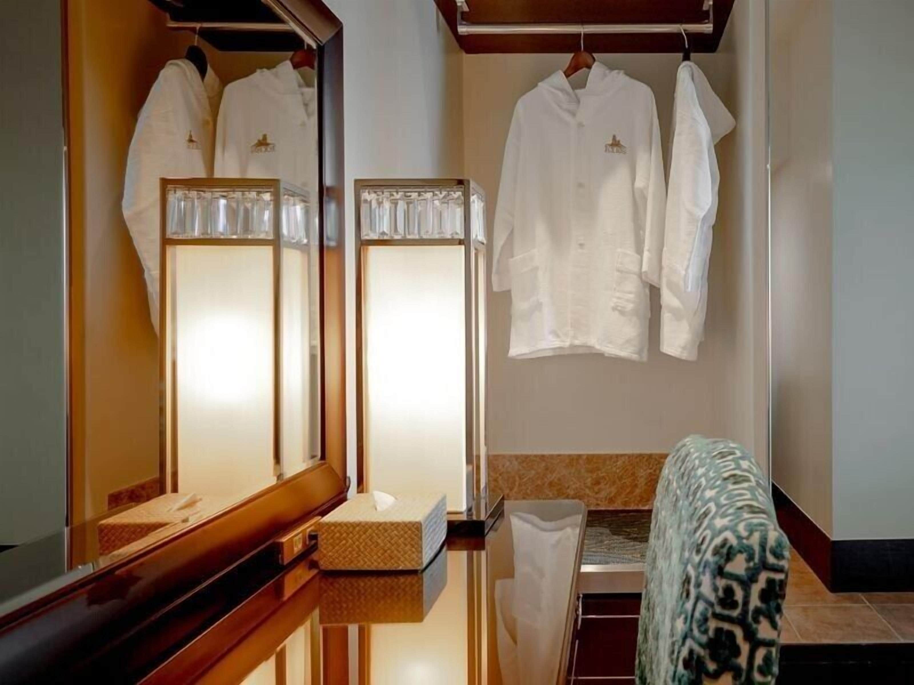 Una camera d'albergo con uno specchio, una panca di legno e un divano a fantasia.