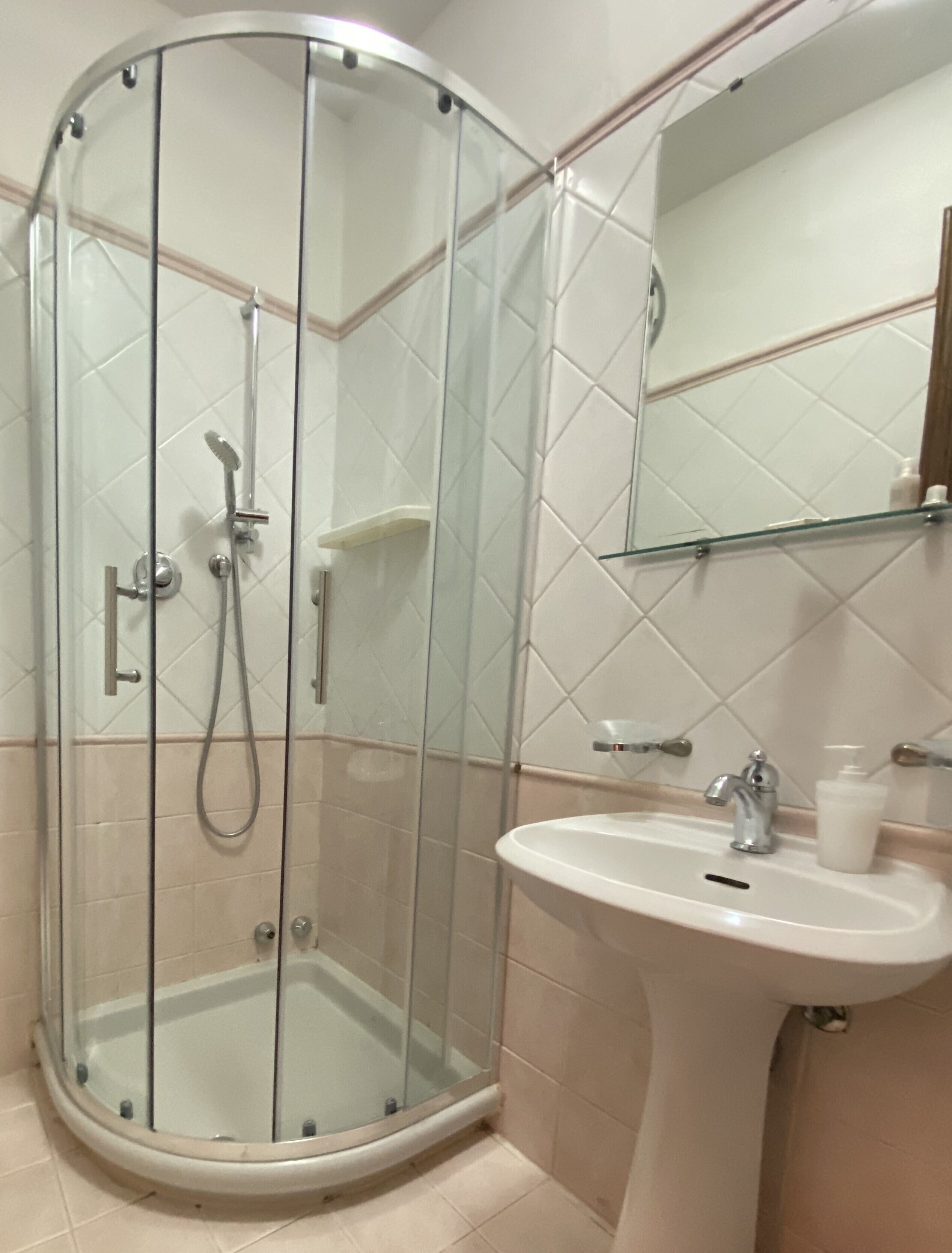 Une salle de bain avec une douche à parois de verre, un lavabo et un miroir.