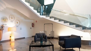A modern lobby with a glass staircase, a seating area with a glass table, and a fire extinguisher on the wall. - Cristal Palace Hotel (Andria)