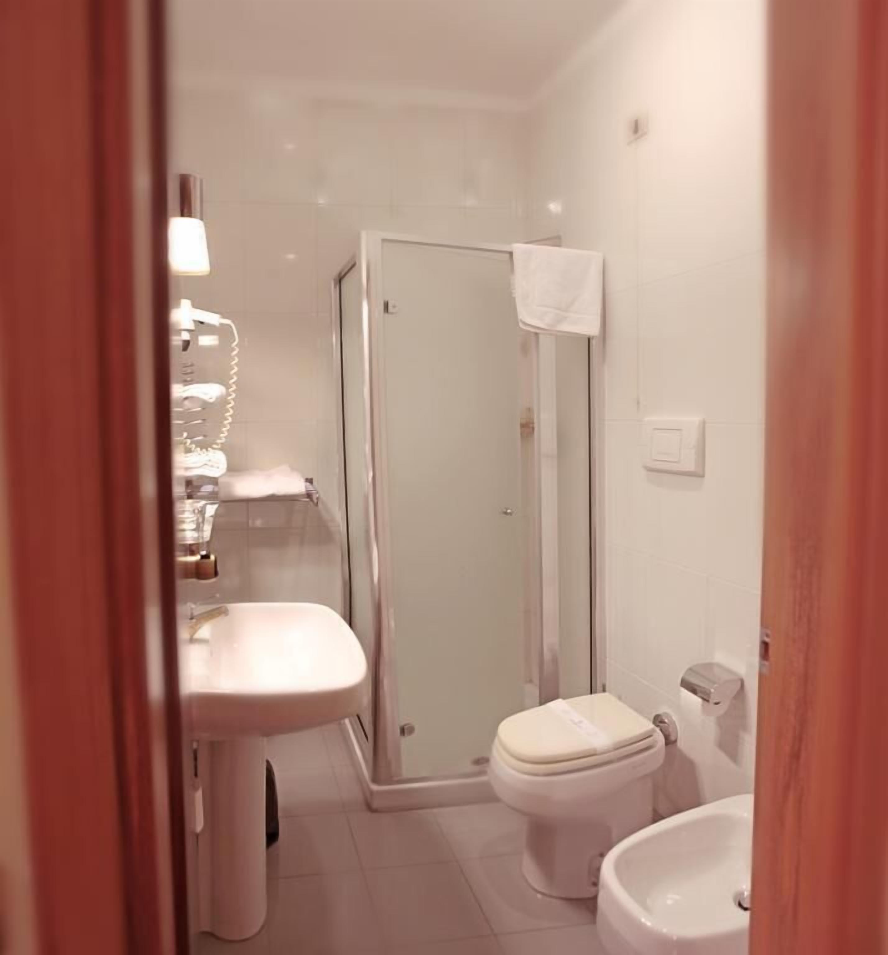 Un bagno piccolo e moderno con cabina doccia in vetro, toilette e lavabo.
