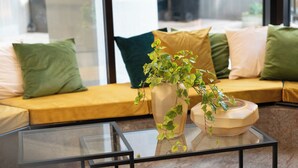 A modern living room with a glass coffee table, a sofa with cushions, and a potted plant. - Cristal Palace Hotel (Andria)