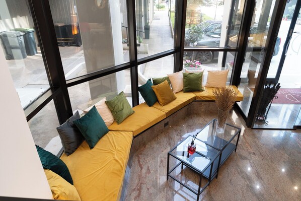 Un intérieur moderne avec un canapé incurvé, une table basse en verre et de grandes fenêtres donnant sur la rue.