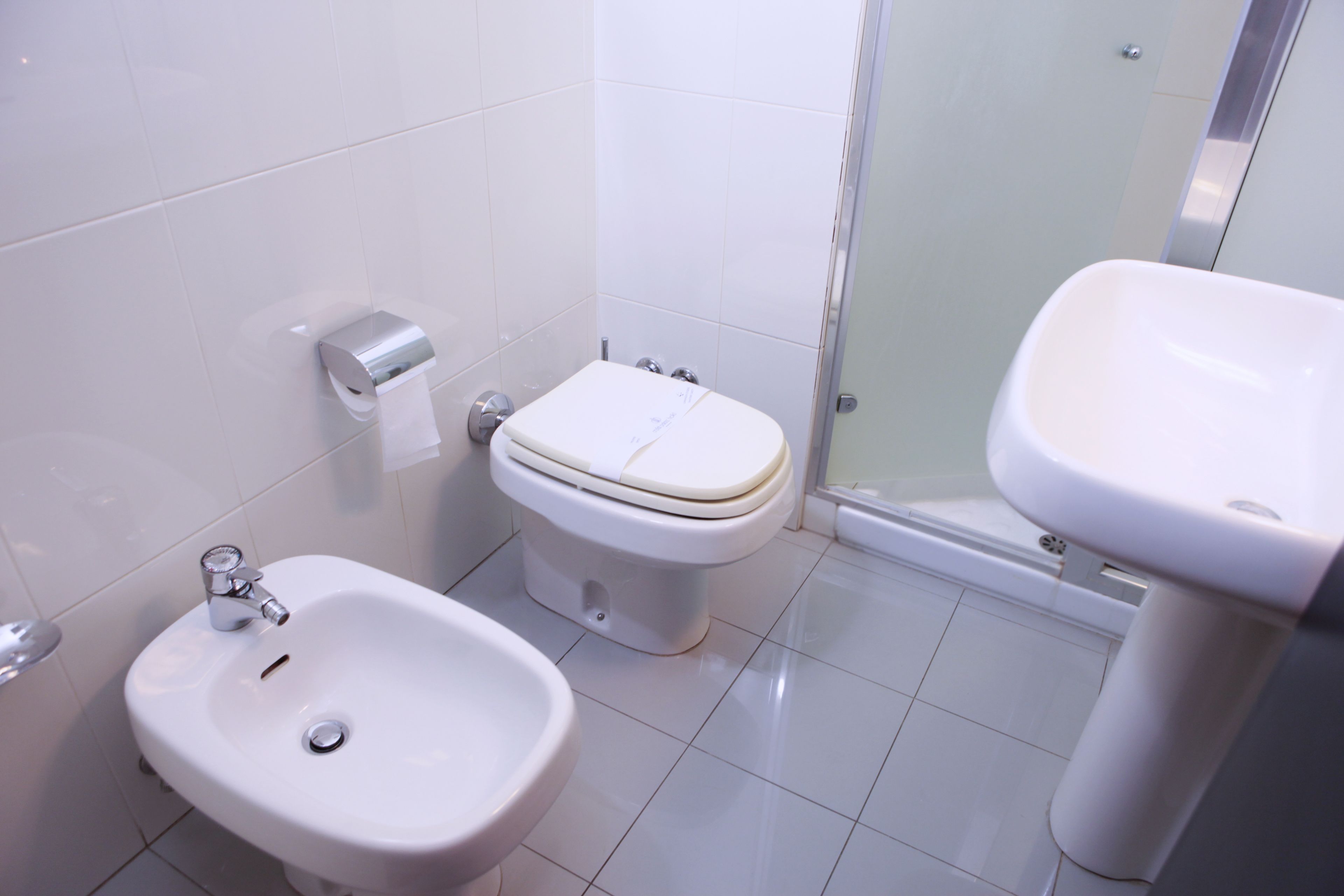 A bathroom with a bidet, toilet, and sink.