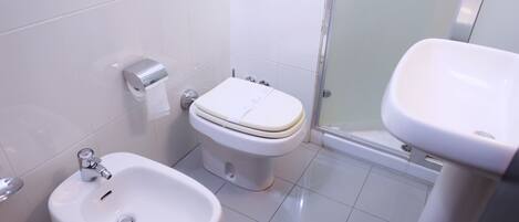 A bathroom with a bidet, toilet, and sink.
